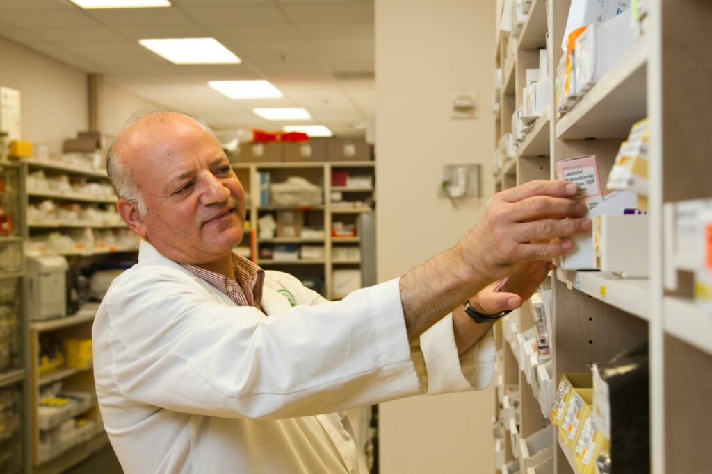 Male pharmacist taking medicines off shelf